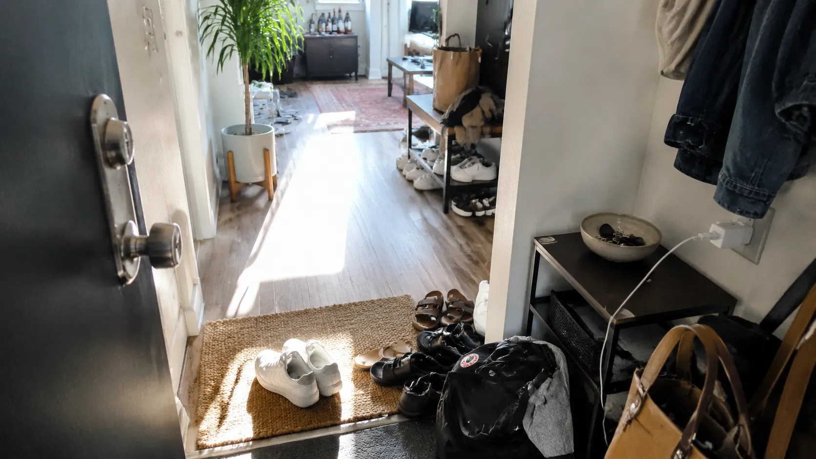 An entryway with visible clutter, cords, light, and one calmer visual anchor showing how a room can feel too fast or more settled.