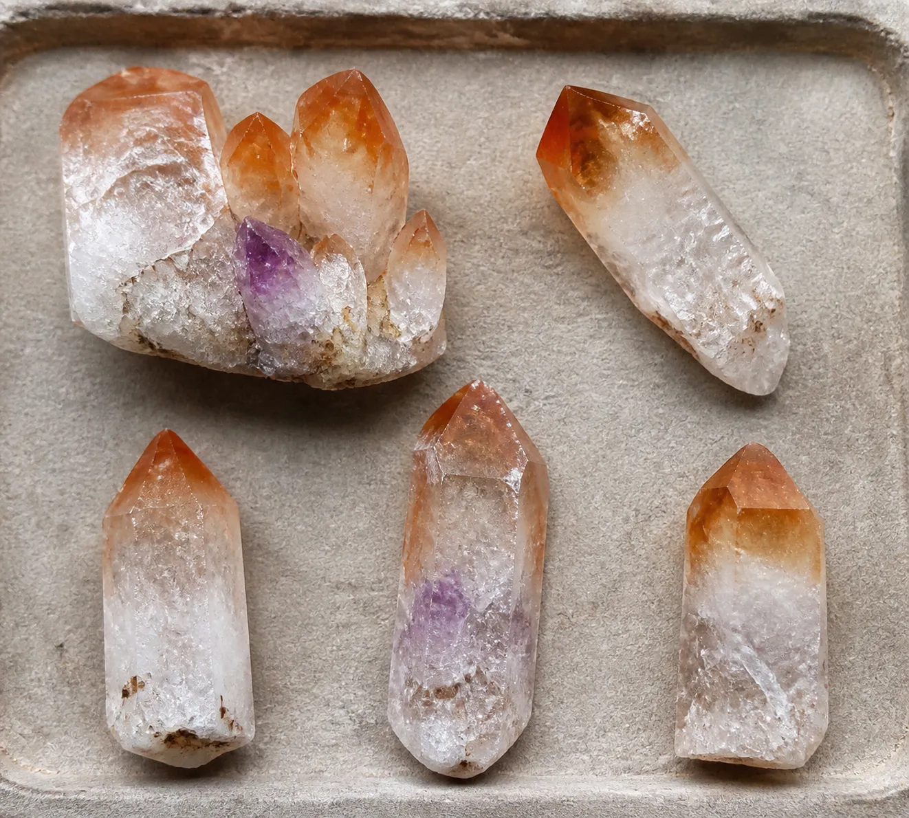 Close comparison view of quartz points with orange tips, pale base color, and small residual purple areas for visual inspection context