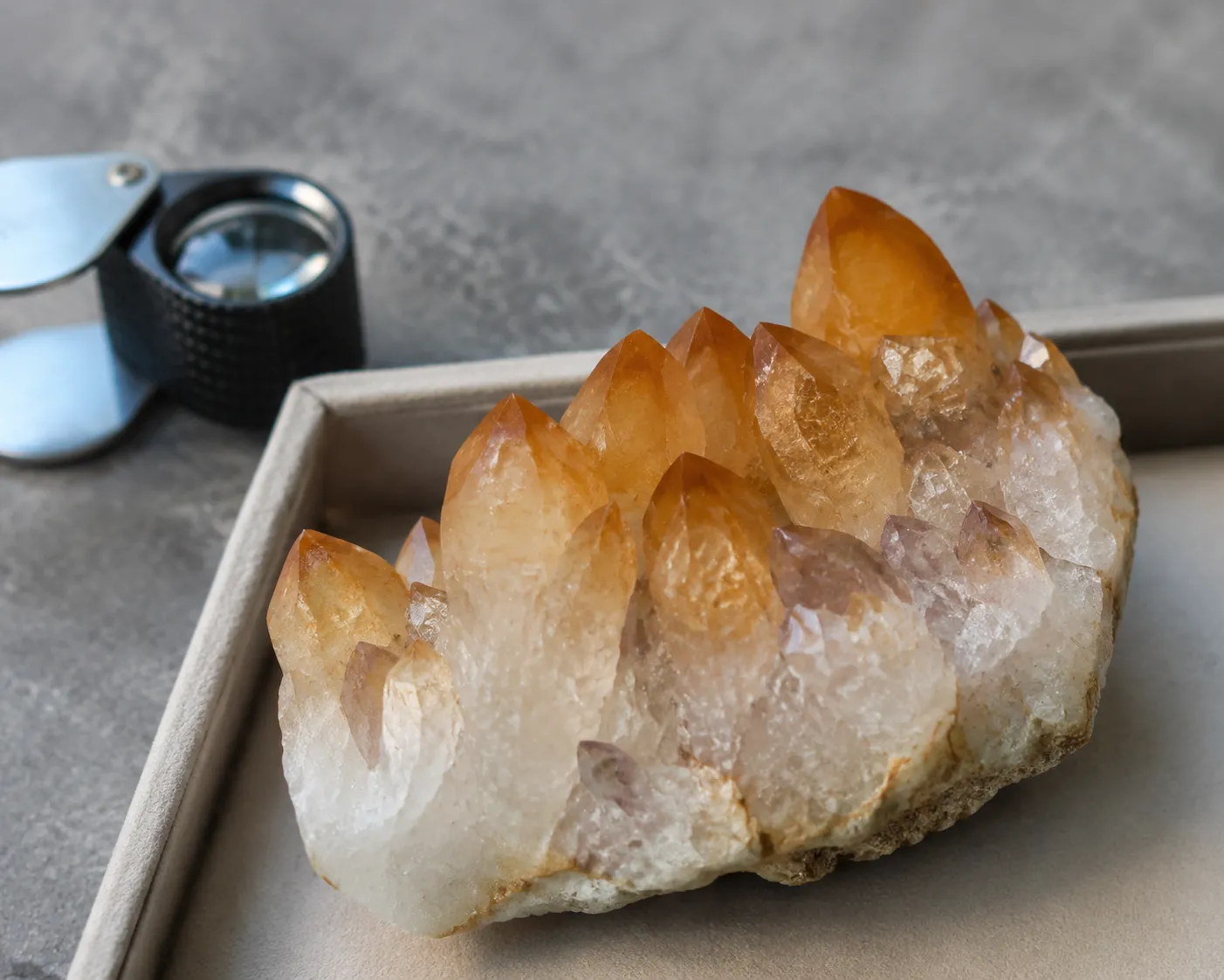Quartz cluster showing burnt orange tips, a pale base, and uneven color zoning that raises suspicion of heat-treated amethyst