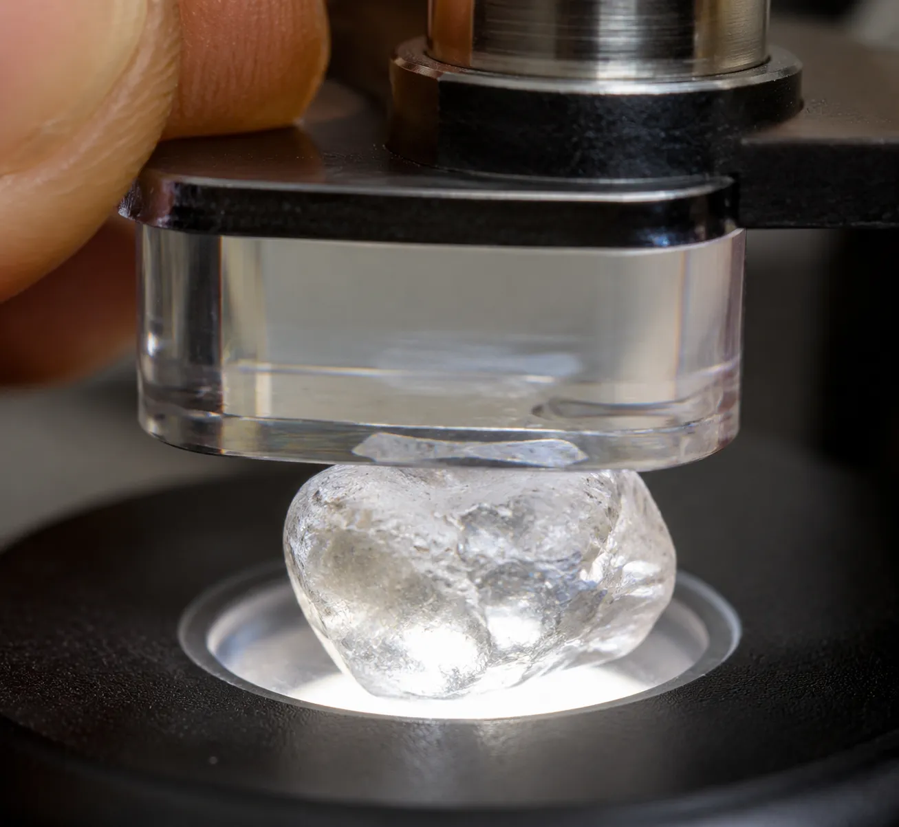 A close view of a calcite dichroscope aligned with a small quartz stone under strong white light.