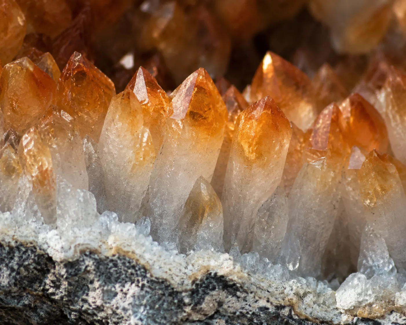 Close view of orange quartz crystal tips with paler bases inside a geode specimen